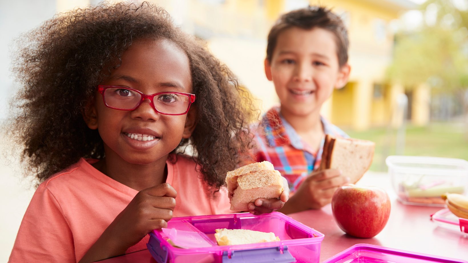 school aged children smiling while eating lunch